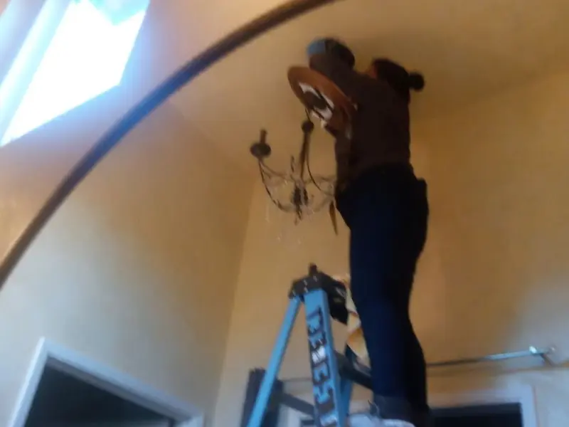 Electrician installing a chandelier in a Marina residence